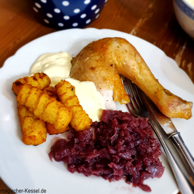 Teller auf Tisch, darauf: Huhn, Kroketten, selbstgemachtes Rotkraut